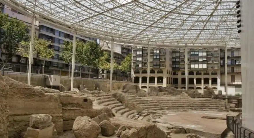 Antiguas ruinas romanas en Zaragoza, protegidas bajo una moderna estructura de cristal y metal.