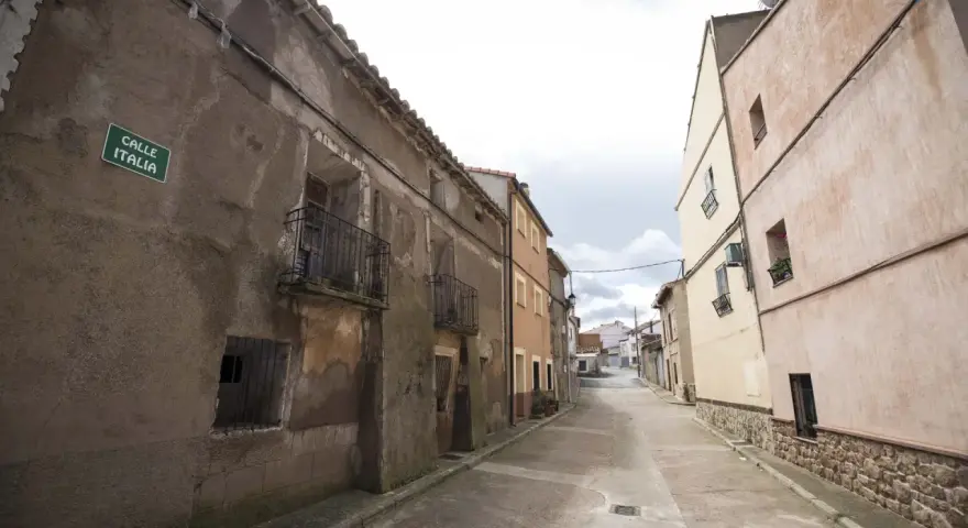 Calle Italia en Villar del Salz, un pueblo con casas antiguas y un cielo nublado.