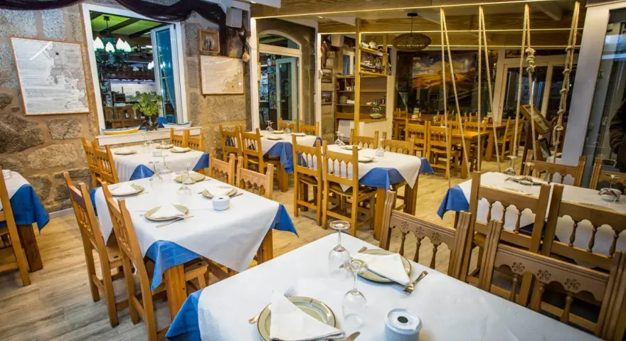 Mesas puestas y listas para comer en Muxía. Ambiente acogedor con decoración marinera, perfecto para disfrutar de la gastronomía local.