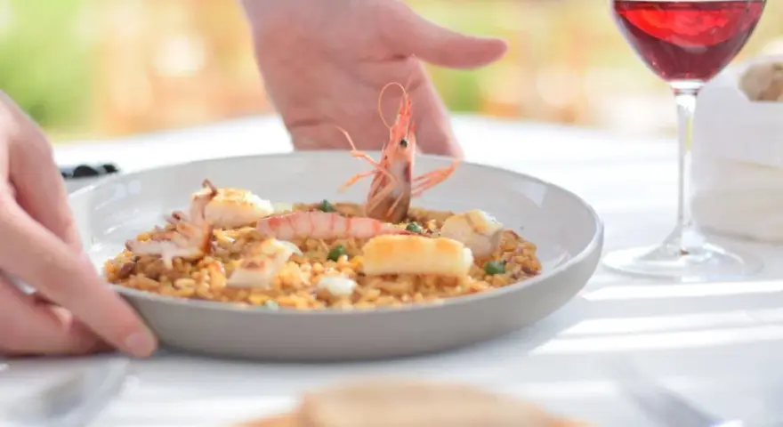 Un plato de paella de marisco servido con vino tinto, ideal para saber donde comer en Menorca.