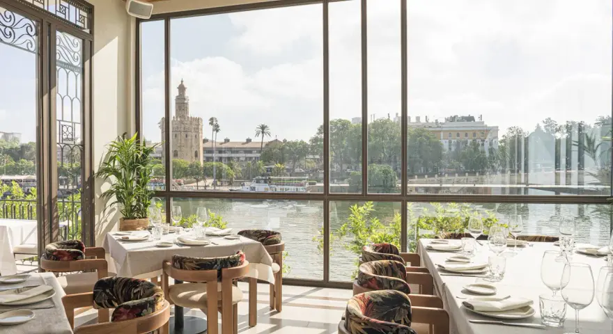 Mesas elegantemente puestas con vistas a la Torre del Oro. Un lugar ideal para disfrutar de una experiencia culinaria en el mejor restaurante Sevilla.
