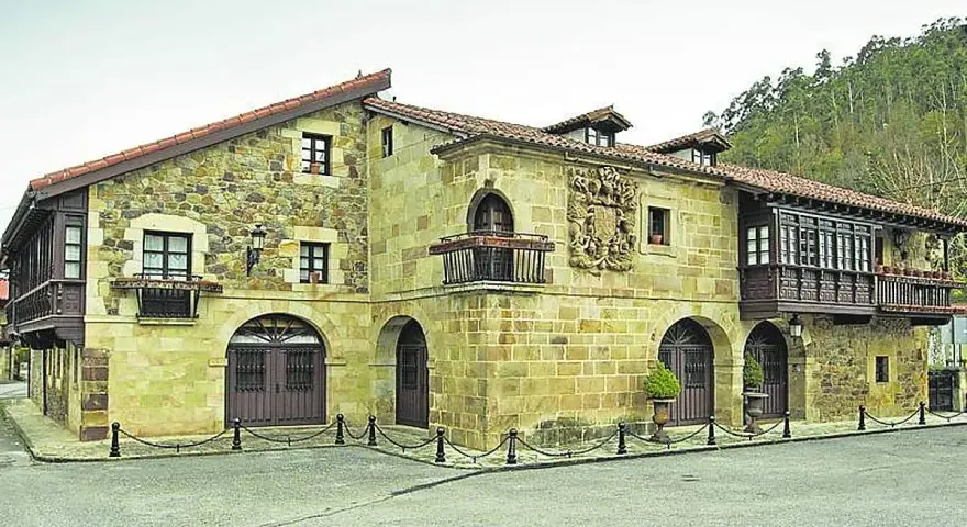 Edificio histórico de piedra con balcones de madera, ideal para saber donde comer en Lierganes.