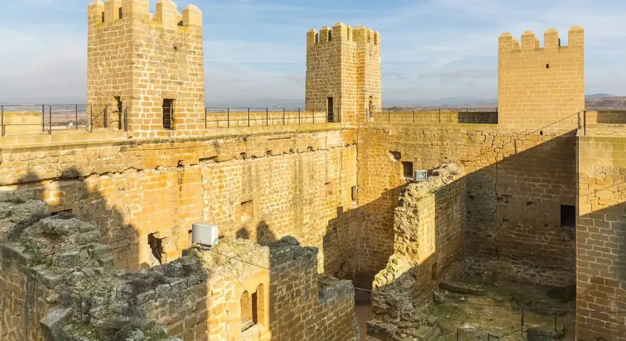 El castillo de Sádaba, con sus imponentes torres de piedra dorada, se alza bajo un cielo azul, invitando a imaginar batallas y leyendas.