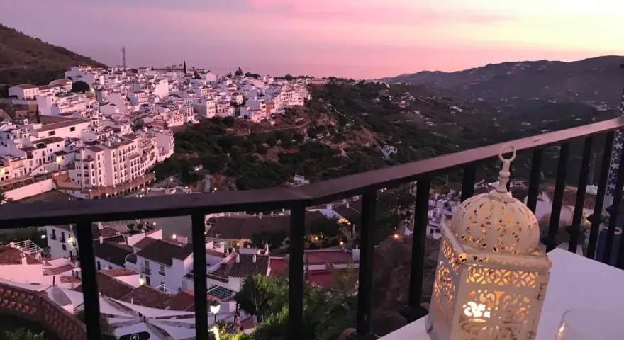 Atardecer rosado sobre Frigiliana. Una linterna ilumina la mesa, perfecta para decidir dónde comer en Frigiliana.