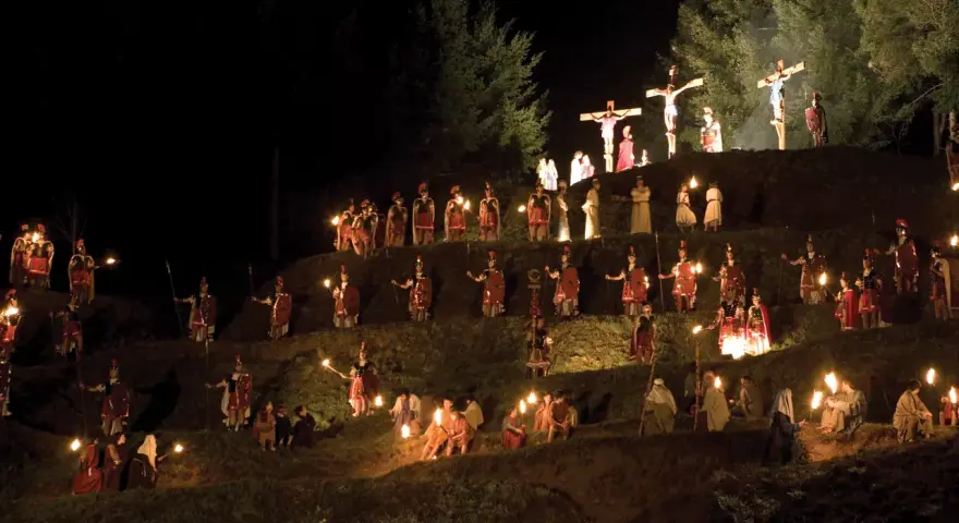 Representación nocturna del vía crucis en Sant Hilari, con antorchas iluminando a soldados romanos y figuras bíblicas en una ladera.