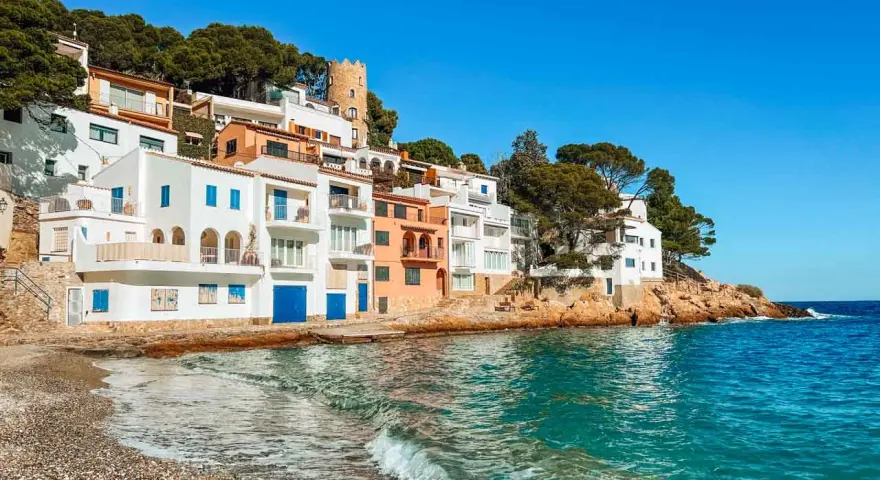 Pueblo blanco en la costa, ideal para tu guía Costa Brava. Casas blancas y naranjas con vistas al mar turquesa.