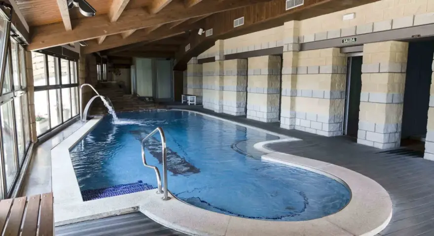Piscina interior con cascadas y escaleras de piedra, ideal para relajarse en las **Vilas del Turbon**.