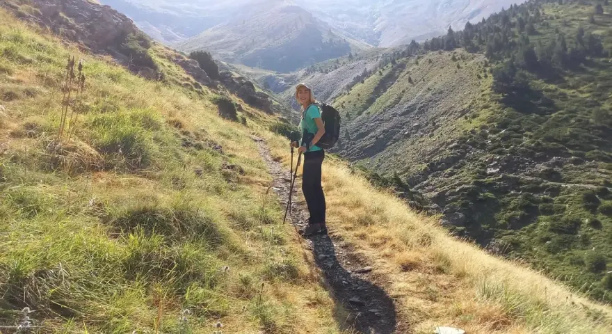 Senderista en el **valle de Chistau**, disfrutando de la vista de las montañas y la vegetación.