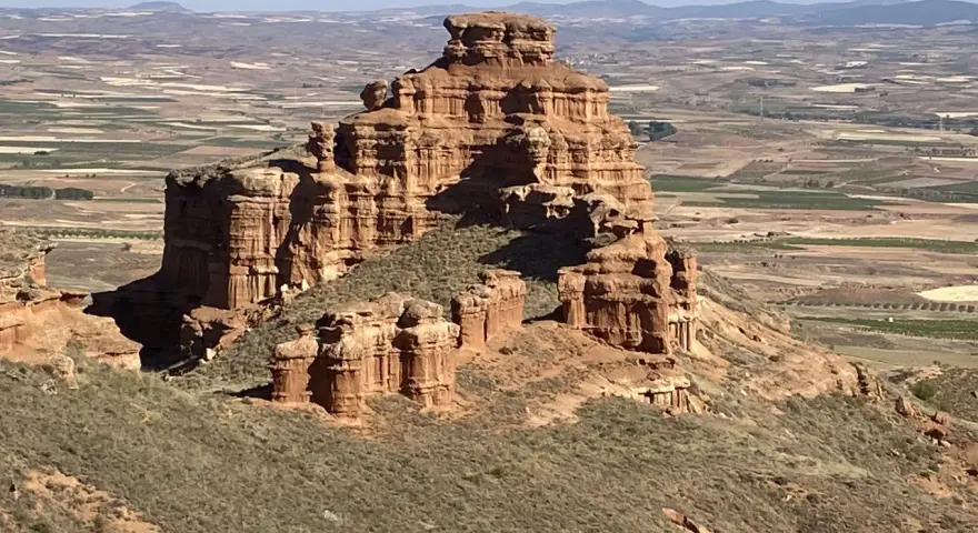 Impresionante formación rocosa en Villarroya de la Sierra, con un paisaje de campos cultivados al fondo.