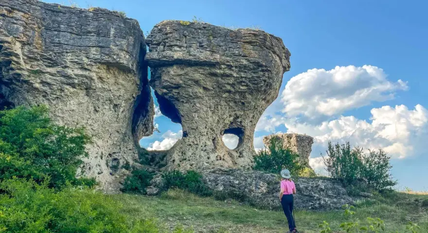 Una persona observa formaciones rocosas únicas, como si fueran las tuerces ruta circular, bajo un cielo azul con nubes.