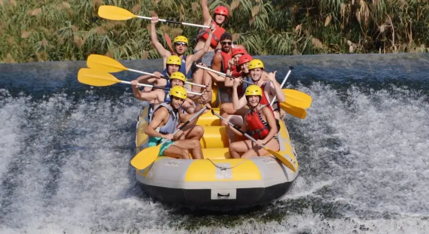 Un grupo de personas disfruta del rafting, remando con entusiasmo en una balsa amarilla sobre aguas turbulentas. ¡Una aventura emocionante!