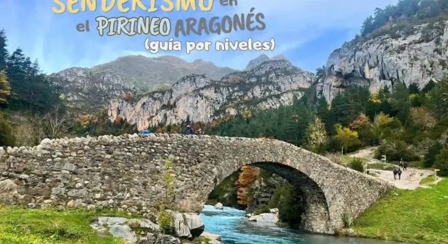 Puente de piedra sobre río turquesa en la montaña de Pirineos. Senderismo en el Pirineo Aragonés.