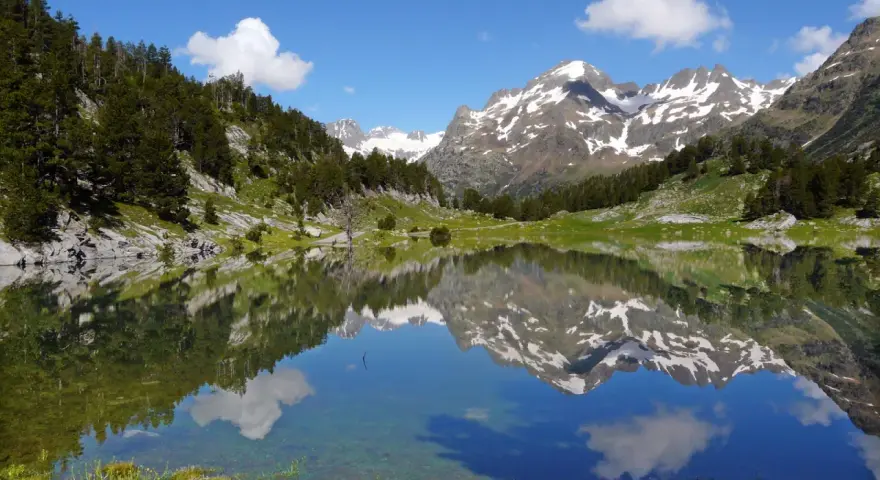 Espectacular reflejo de montañas nevadas y bosques en un lago sereno. Un lugar ideal que ver en el Pirineo Aragonés para conectar con la naturaleza.