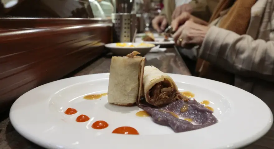 Dos rollitos de carne deshebrada con puré morado y salsa, un delicioso bocado para comer en Plasencia.