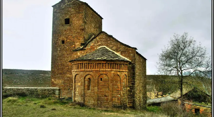 Antigua iglesia románica de piedra, una de las iglesias del Serrablo, con su torre cuadrada y ábside semicircular.