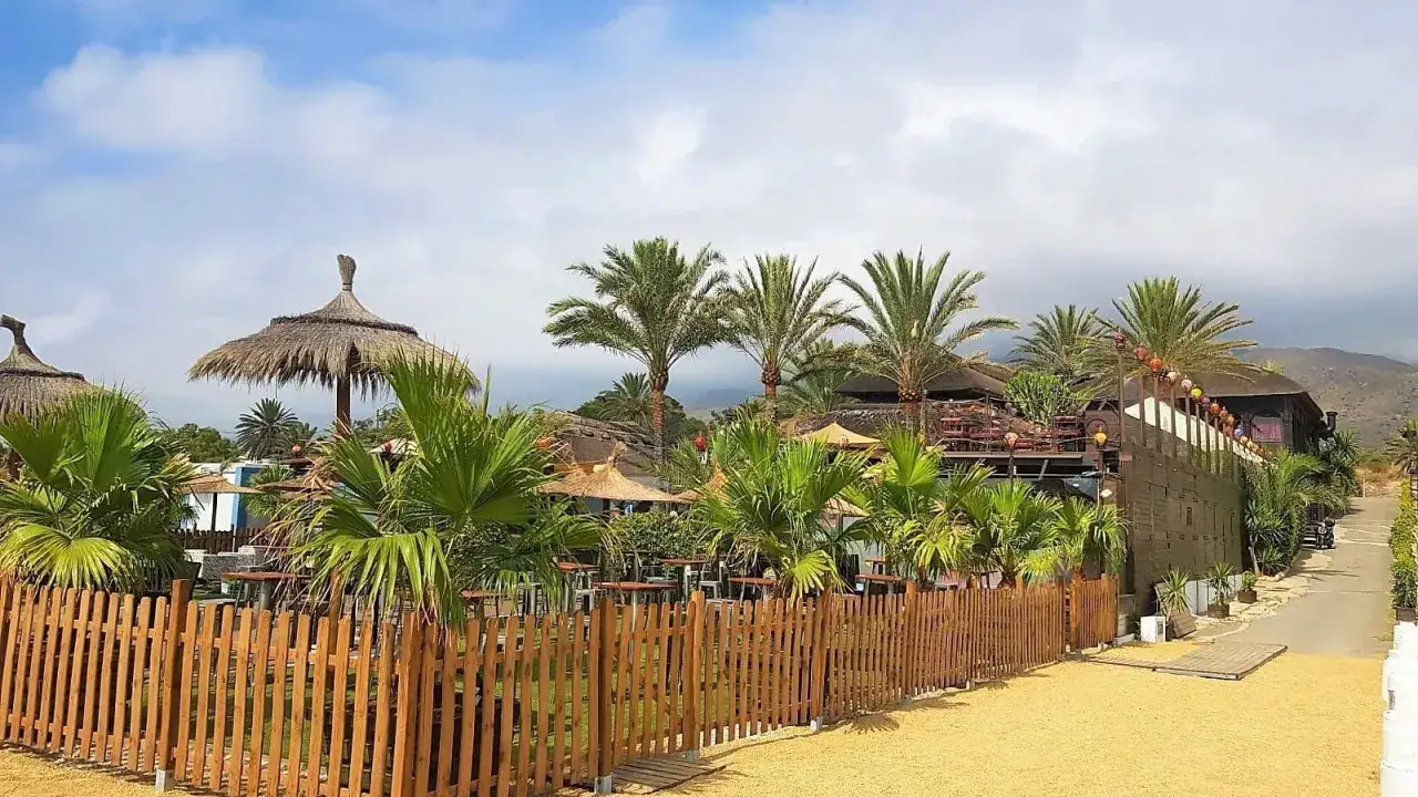 Un lugar ideal donde comer en Mojácar: un chiringuito con palmeras, sombrillas de paja y un ambiente playero.