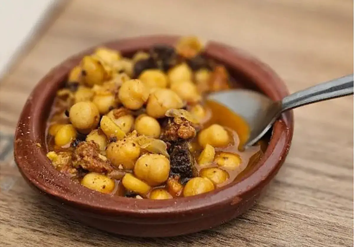 Un plato de barro con garbanzos y trozos de carne, listo para comer en ronda.