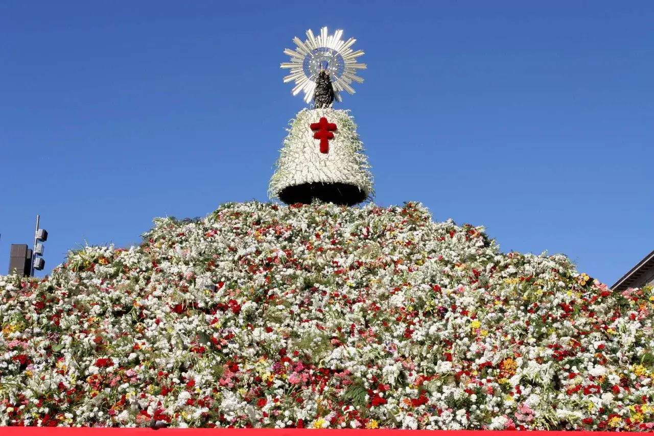 Una enorme montaña de flores blancas y rojas corona una figura de la Virgen con un halo solar, parte de las tradiciones de Aragón.