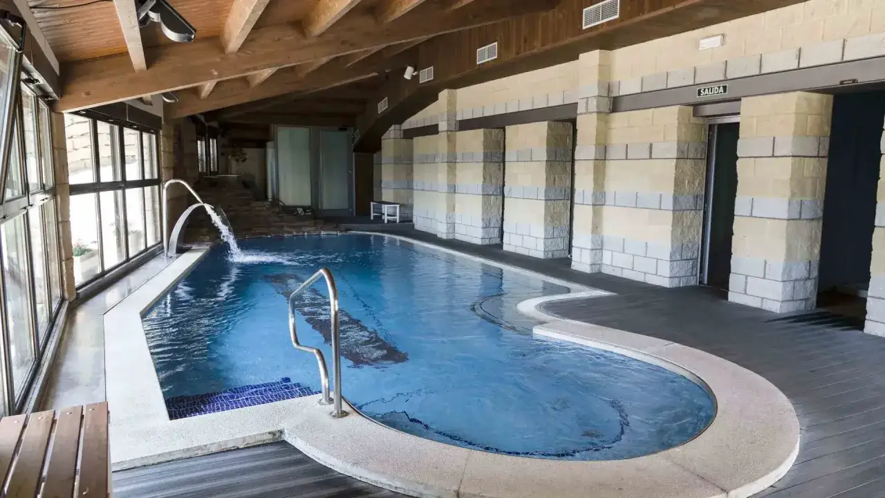 Piscina interior con cascadas y escaleras de piedra, ideal para relajarse en las Vilas del Turbon.