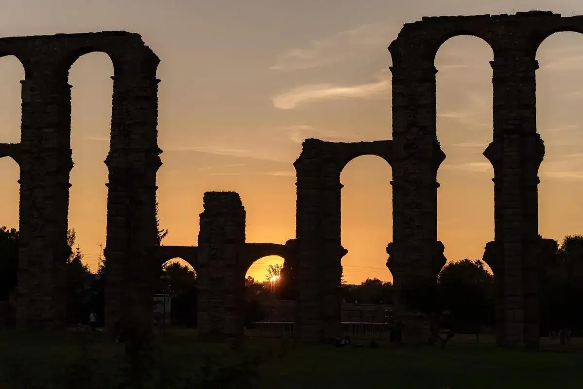 Atardecer en el Acueducto de los Milagros, un imprescindible que ver en M&eacute;rida. Siluetas romanas contra el cielo anaranjado.