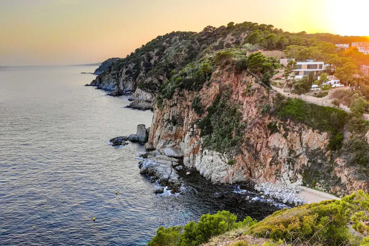 Impresionantes miradores en la Costa Brava, con acantilados rocosos, mar azul y una villa moderna.