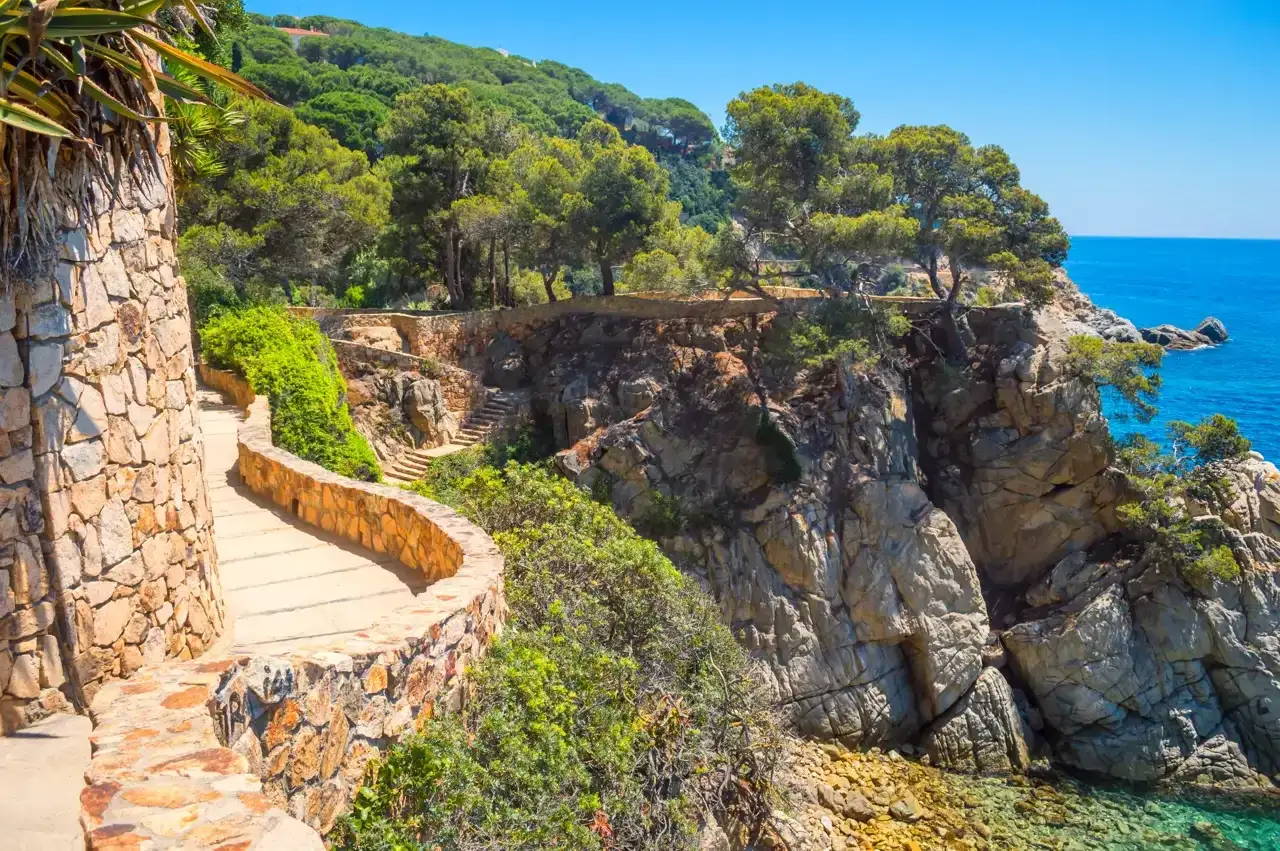 Camino de piedra con vistas al mar azul, ideal para tu guía Costa Brava. Naturaleza y senderismo.