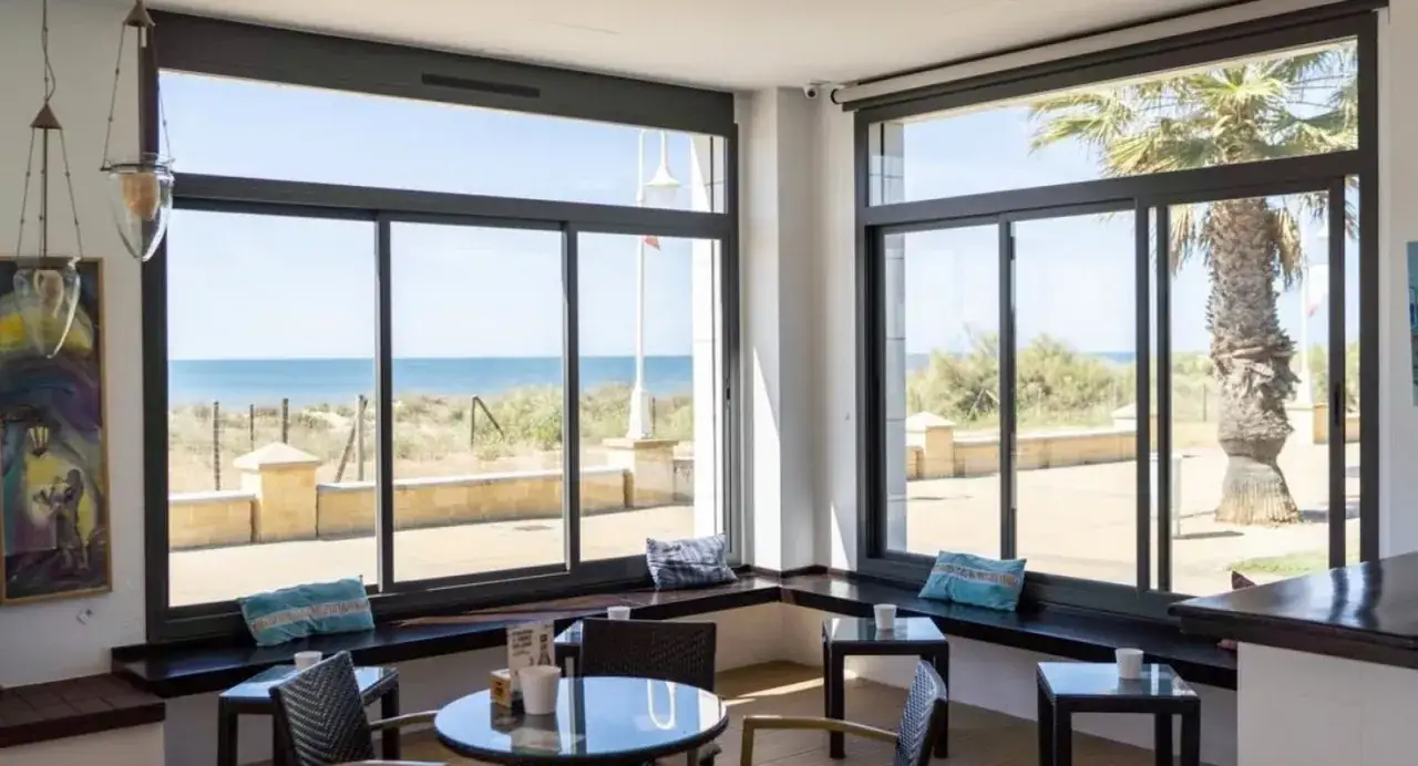 Interior de un restaurante con vistas al mar, ideal para saber donde comer en Islantilla. Mesas, sillas y cojines azules.