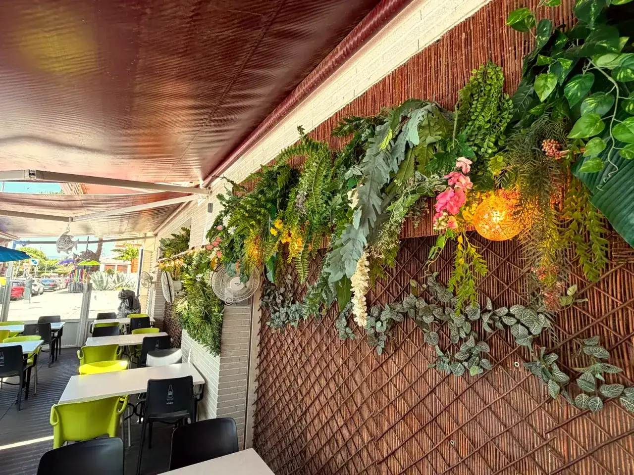 Terraza de restaurantes en Blanes con decoración exuberante de plantas y flores, mesas listas para recibir comensales.