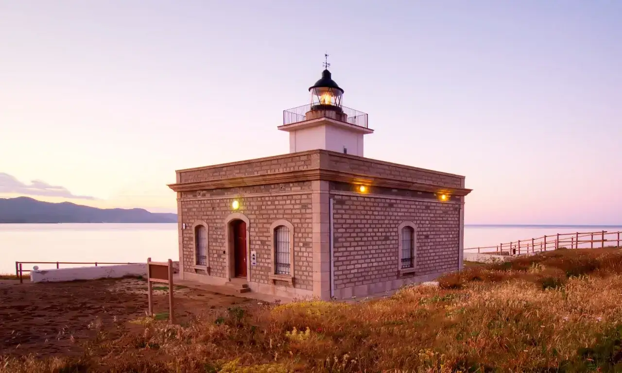 Faro de piedra con vistas al mar al atardecer, cerca del far port de la selva.