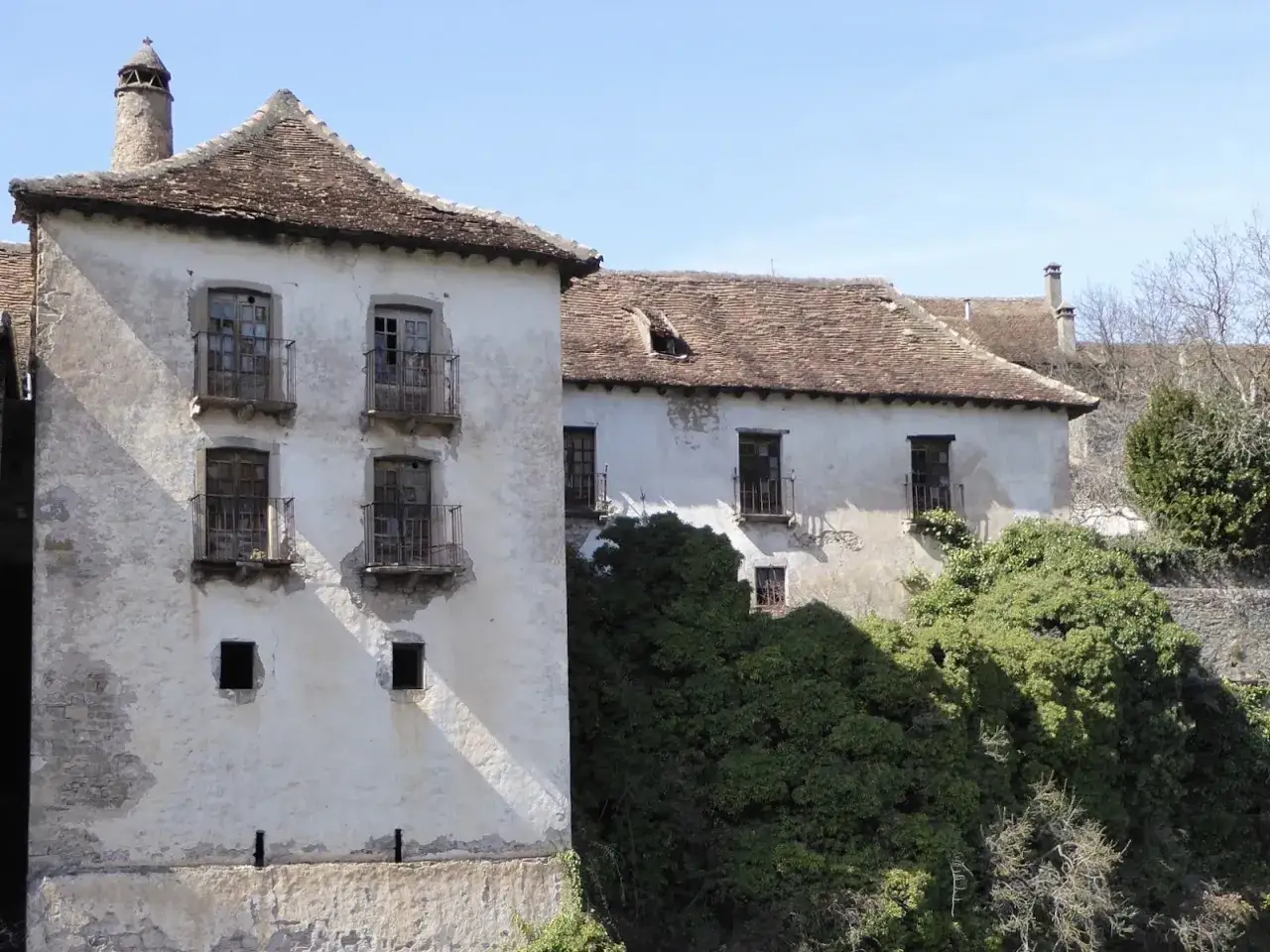 Antiguas casas en Aragues del Puerto, con tejados de teja, balcones de hierro y vegetaci&oacute;n exuberante cubriendo parte de las fachadas.