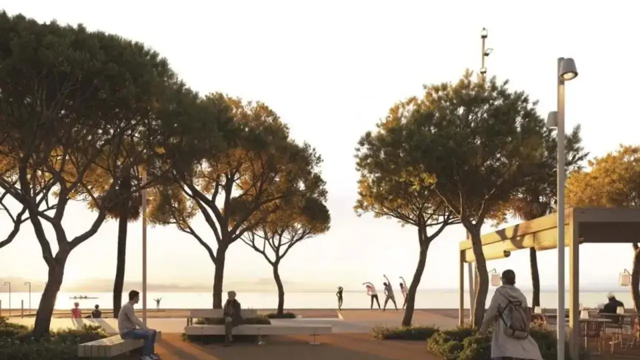 Gente haciendo ejercicio y relajándose en la playa de Aro centro, con árboles y el mar de fondo.