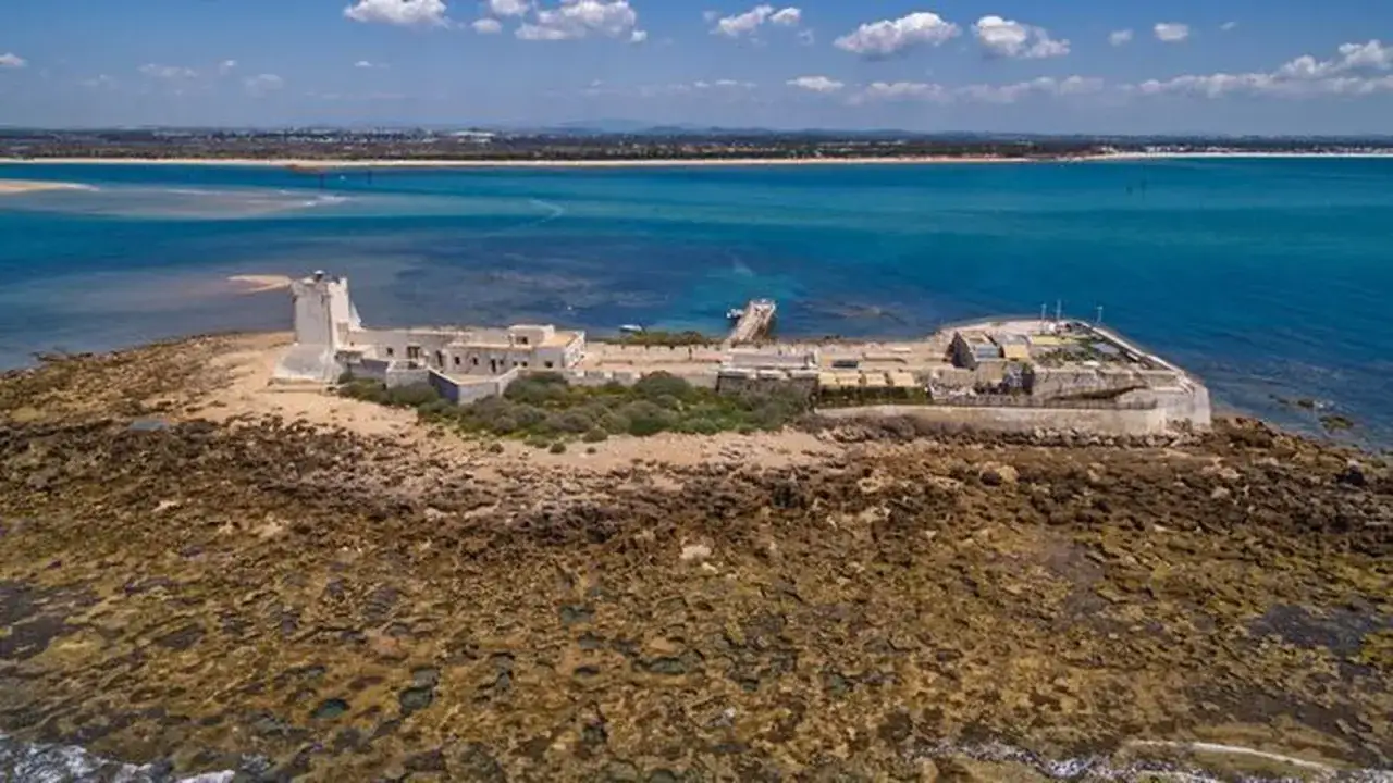 Fortaleza de Sancti Petri que ver: antigua fortificación en una isla rocosa, rodeada por el mar azul.