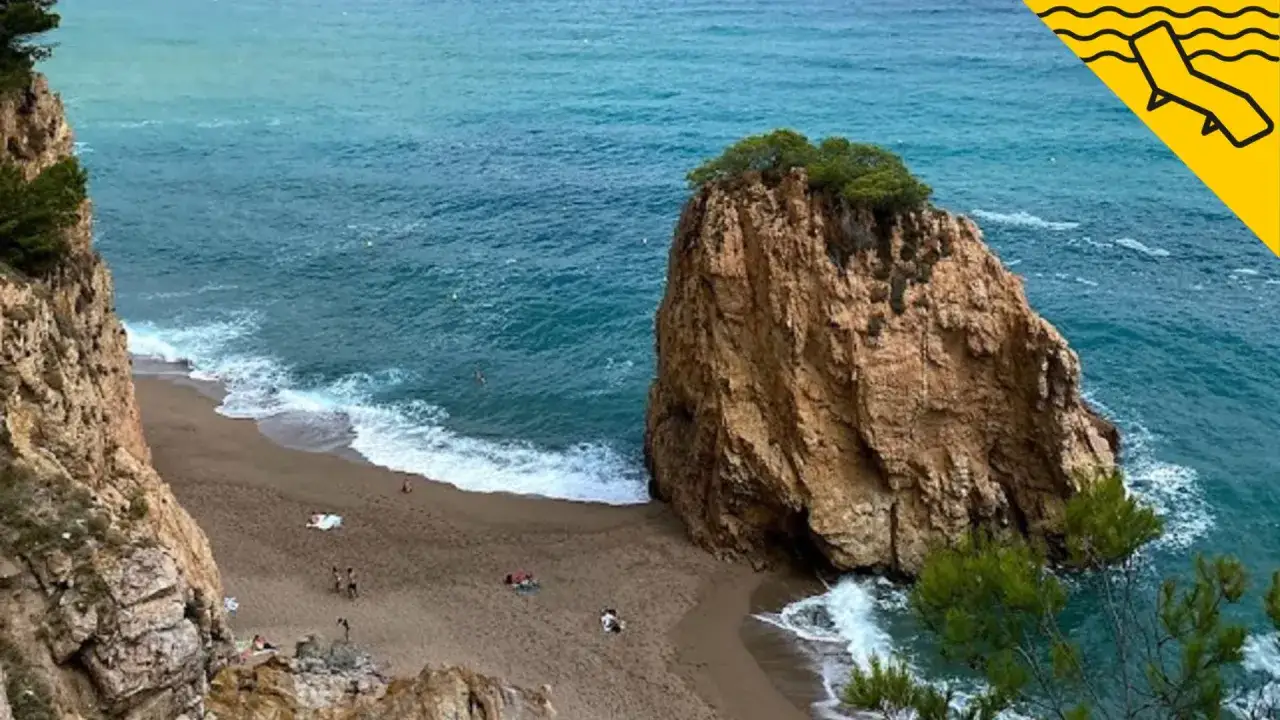 Una cala rocosa con arena dorada y aguas turquesas, ideal para disfrutar de la playa nudista en Cadaqués.