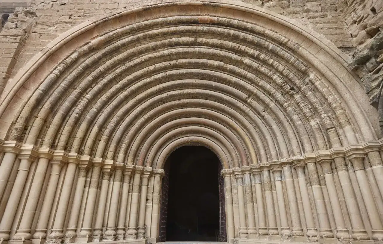 Imponente entrada románica del monasterio de Siresa, con arcos concéntricos y columnas talladas que invitan a entrar.