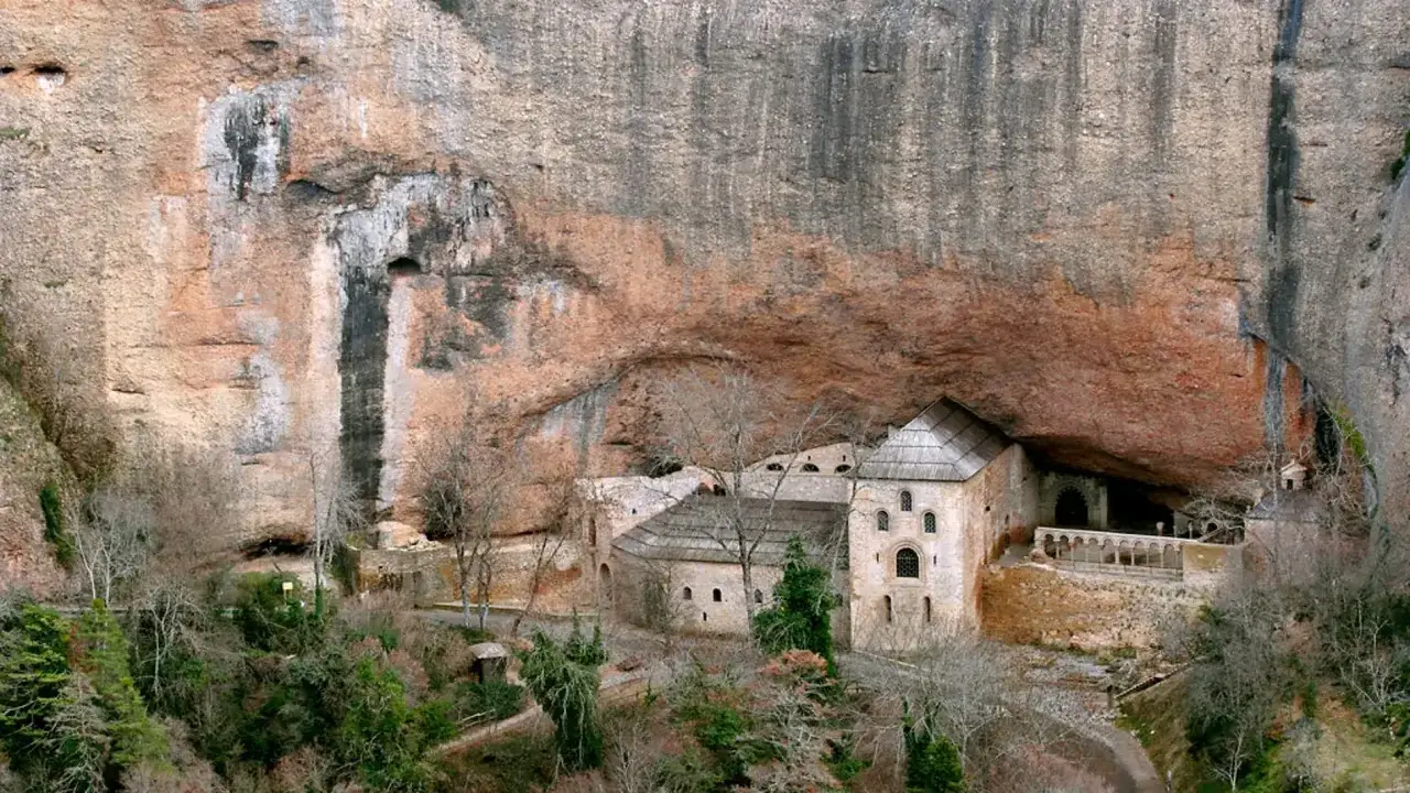 Monasterio de San Juan de la Peña, incrustado en una roca, con arquitectura de piedra y tejados a dos aguas.