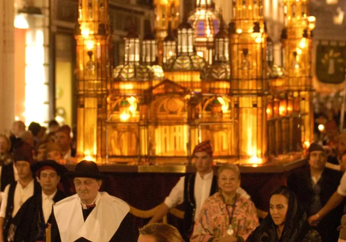 Gente observa un elaborado rosario de cristal Zaragoza iluminado, parte de una procesi&oacute;n festiva.