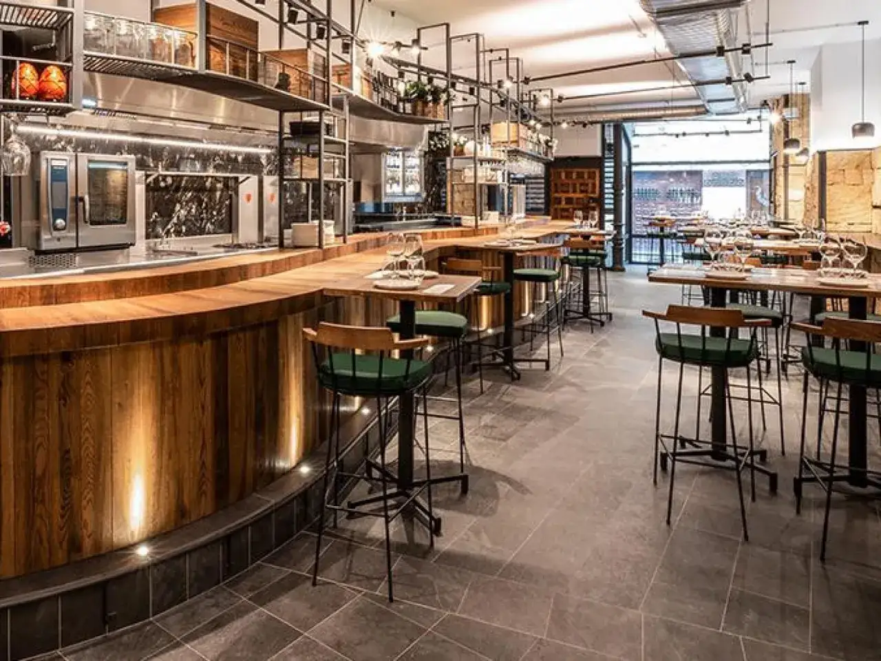 Bar moderno con taburetes verdes y mesas. Un lugar ideal para saber donde comer en Salamanca.