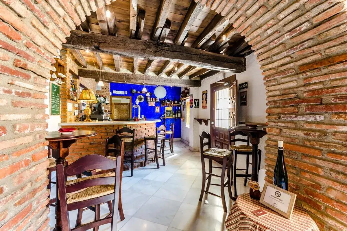 Bar r&uacute;stico con paredes de ladrillo y vigas de madera. Ideal para saber donde comer en Guadix.