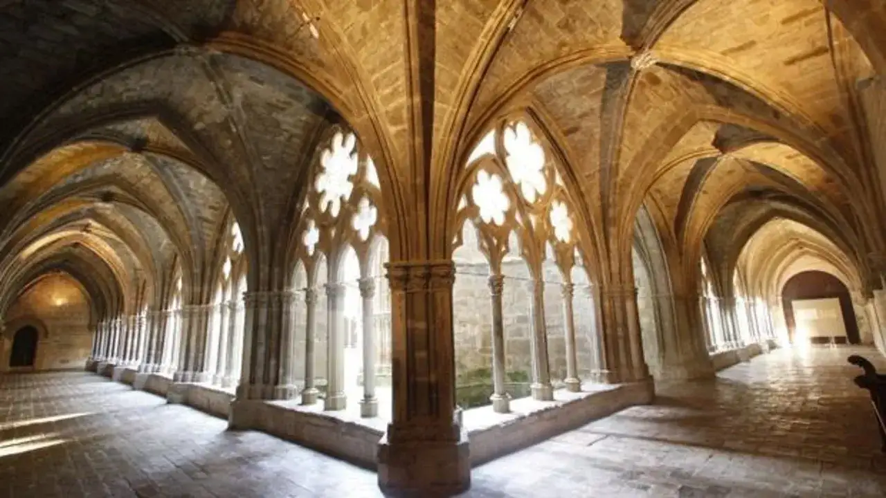 Pasillos abovedados y columnatas del monasterio de Veruela, con luz filtrándose por ventanales góticos.