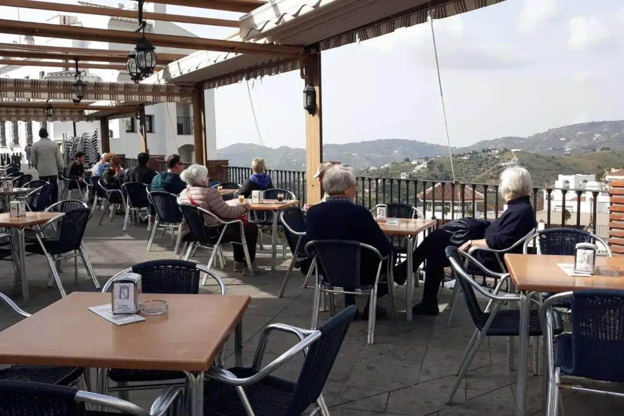 Gente disfrutando en un restaurante con vistas. Un lugar ideal donde comer en Frigiliana para relajarse y admirar el paisaje.