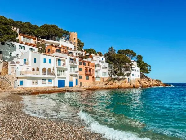 Pueblo blanco en la costa, ideal para tu guía Costa Brava. Casas blancas y naranjas con vistas al mar turquesa.