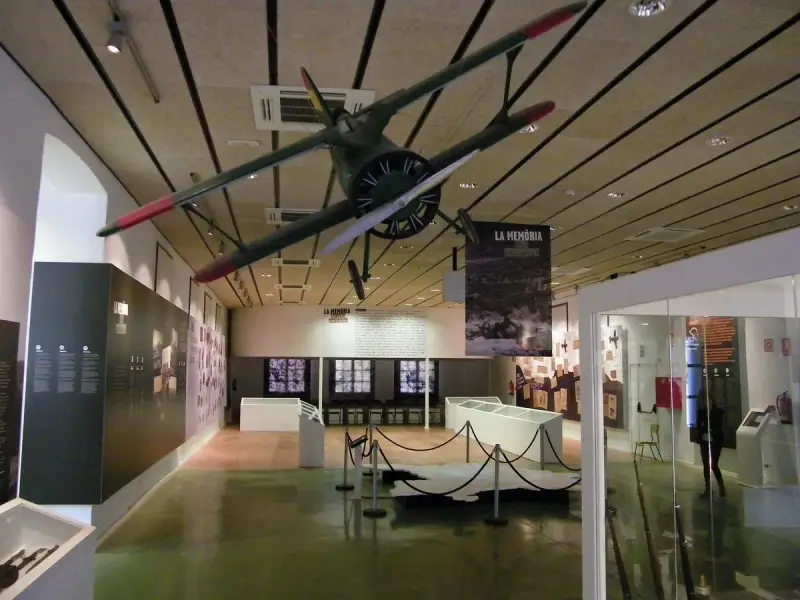 Interior del museo de la Batalla del Ebro, con un avión colgado del techo y expositores.