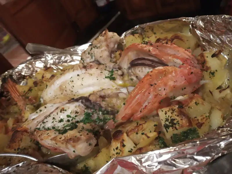 Delicioso pescado y gambas al horno con patatas, un plato típico de la casa Juanita Begur.
